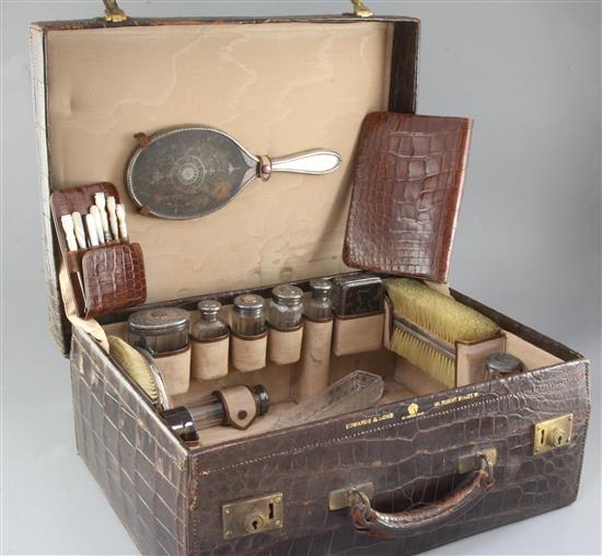 A late Victorian Edwards & Sons crocodile skin travelling toilet case containing assorted silver and tortoiseshell bottles etc.